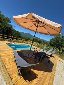 a table and chairs under an umbrella next to a pool at GrappoloNero in Laino Castello