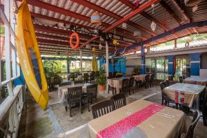 a restaurant with tables and chairs and a surfboard on the wall at Vicina Maris Beach Lodge in María Chiquita