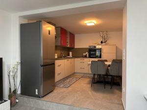 a kitchen with a refrigerator and a table with chairs at Modernes Appartment in Schifflange in Schifflange