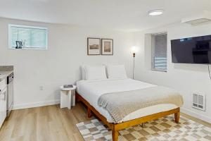 a white bedroom with a bed and a flat screen tv at The Gordon Getaway in Seattle