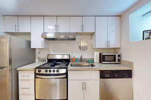 a kitchen with white cabinets and a stove and a sink at The Gordon Getaway in Seattle +4 photos
