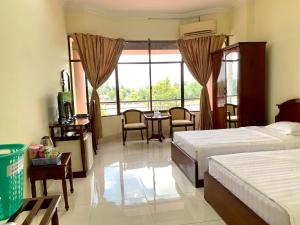 a bedroom with two beds and a table and chairs at Hung Vuong Hotel in Ben Tre +32 photos