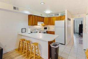 a kitchen with wooden cabinets and a white refrigerator at Jamaica Bay 105A in Ocean City