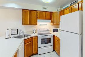 a kitchen with wooden cabinets and a white refrigerator at Jamaica Bay 105A in Ocean City