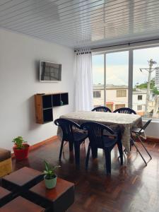 a living room with a table and chairs and a large window at Arboleda in Manizales