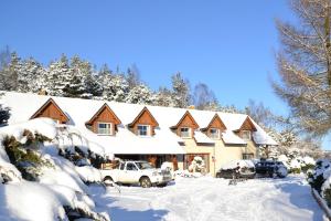 dom pokryty śniegiem z samochodami zaparkowanymi na podjeździe w obiekcie Koziołkowo w mieście Bartoszylas