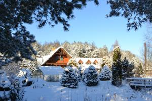 un jardín cubierto de nieve con una casa en el fondo en Koziołkowo, en Bartoszylas