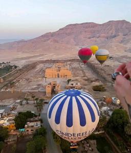 three hot air balloons flying over a desert at Flower House in Al Aqālitah +7 photos