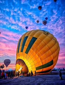 a group of hot air balloons flying in the sky at Flower House in Al Aqālitah