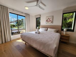a bedroom with a large bed with two windows at Amazing 3bd in National Park in Bundeena