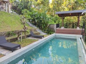 a swimming pool with two chairs and a bench in a yard at Jagadhita sekembang ubud in Ubud
