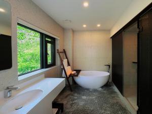 a bathroom with a tub and a sink and a window at Between Trees and Streams in Jiuzhaigou +99 photos