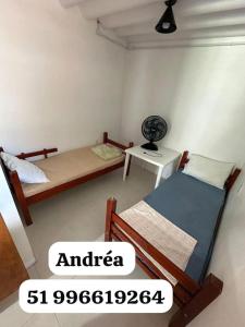 a bedroom with two beds and a desk with a fan at Canto dos pássaros in Tramandaí