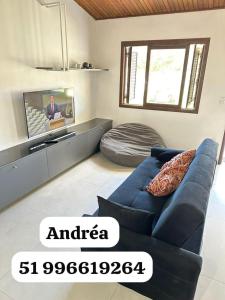 a living room with a blue couch and a tv at Canto dos pássaros in Tramandaí