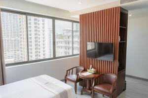 a hotel room with a bed and a tv and two chairs at The ONRA Hotel in Phnom Penh