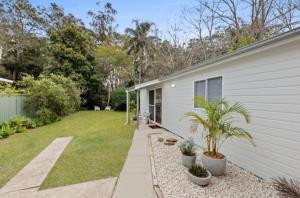 a backyard of a house with plants in a yard at The Seaside Haven Umina in Umina