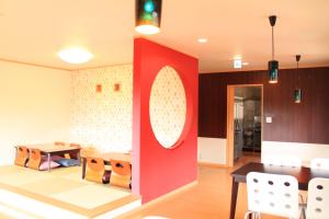 a dining room with a red wall and a table and chairs at ヴィラルミエール in Yamanakako