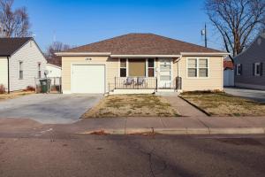 a yellow house with a white garage at Gano Street Retreat in Great Bend
