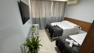 a hotel room with two beds and a television at Loft centro de Goiânia 1108 in Goiânia