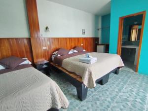a bedroom with two beds and a table with towels at Hospedaje Cactus Experience in Puerto Villamil
