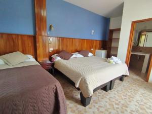 two beds in a hotel room with blue walls at Hospedaje Cactus Experience in Puerto Villamil +2 photos