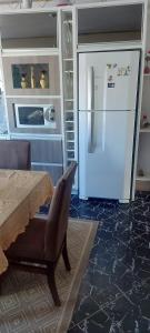 a kitchen with a refrigerator and a table and a chair at Casa Nascer do Sol in Sangão