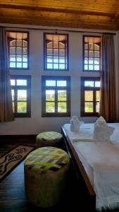 a bedroom with two beds and two ottomans and windows at Sorlesa in Gjirokastër
