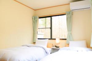 two beds in a room with a window at ヴィラルミエール in Yamanakako