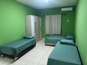 two beds in a room with green walls at Araçagy Casa Mar in São José de Ribamar
