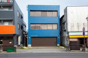 a blue building with a garage in between two buildings at mahoratto in Aomori