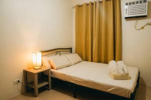 a small bedroom with a bed with a lamp and a window at Cozy 2BR Retreat at 8 Spatial Davao in Davao City +9 photos