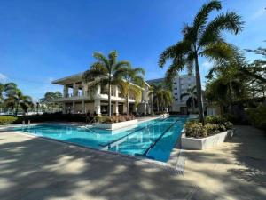 a swimming pool with palm trees in front of a building at Cozy 2BR Retreat at 8 Spatial Davao in Davao City
