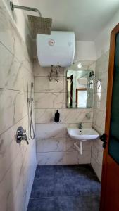 a white bathroom with a sink and a mirror at Sorlesa in Gjirokastër
