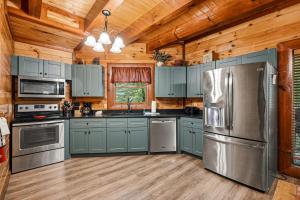 a kitchen with blue cabinets and stainless steel appliances at Cherokee Pool Lodge in Cosby