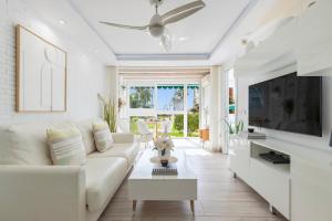 a living room with a white couch and a tv at Luxury White Summer Benalmadena in Benalmádena