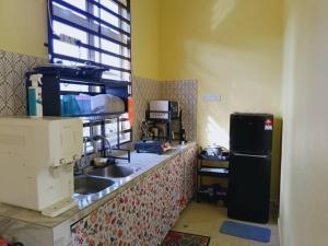a kitchen counter with a sink and a refrigerator at RumahKuningHOMESTAY in Bachok