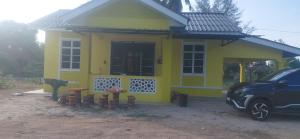 a small yellow house with stools in front of it at RumahKuningHOMESTAY in Bachok