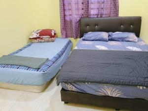 two beds sitting next to each other in a bedroom at RumahKuningHOMESTAY in Bachok