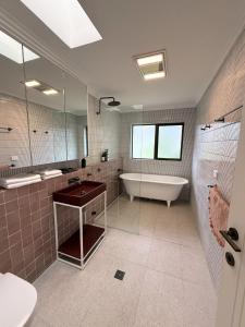 a bathroom with a tub and a toilet and a sink at Amazing 3bd in National Park in Bundeena +63 photos