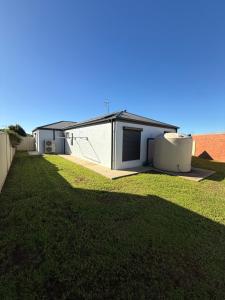 a house with a grass yard next to a building at The Holiday Home Griffith in Griffith