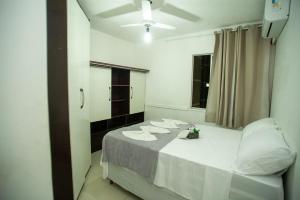 a room with a bed with white sheets and a window at Apartamento Morada dos Sonhos in Lauro de Freitas