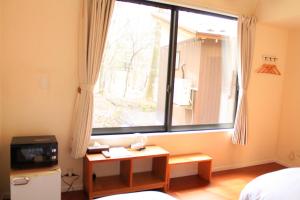 a room with a window with a television and a table at ヴィラルミエール in Yamanakako