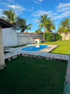 a backyard with a swimming pool and palm trees at Casa de Praia do Morro Branco in Beberibe