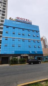 a blue building with a car parked in front of it at Hotel Panamericano in Lima
