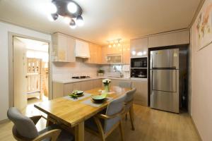 a kitchen with a wooden table with chairs and a refrigerator at 옥상달빛 게스트하우스 in Seoul