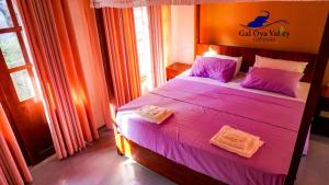 a bedroom with a bed with purple sheets and pillows at Gal Oya Valley Cottages in Ampara