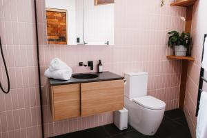 a pink bathroom with a sink and a toilet at Charm on Forster in Invermay