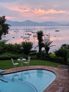 a swimming pool with chairs and boats in the water at Woodpecker cottage in Hartbeespoort
