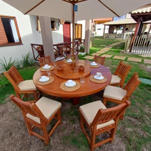 a wooden table with chairs and an umbrella at Kite House Lençóis II in Santo Amaro