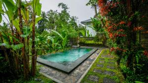 a swimming pool in the middle of a garden at The Oding House in Ubud